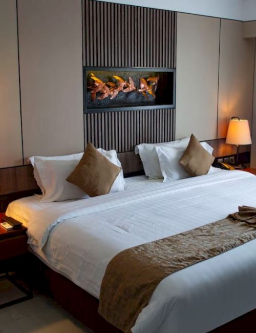 A modern hotel room with a large bed, bedside tables with lamps, a wall-mounted art piece, and a window with curtains.