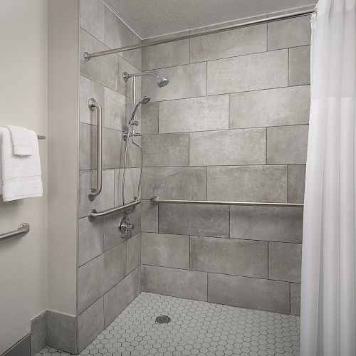 This image shows a modern shower area with a tiled wall, a shower curtain, and two towel racks holding white towels.