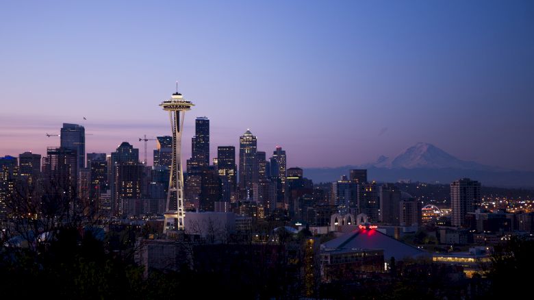 This image features the Seattle skyline at dusk, with the Space Needle prominently visible and Mount Rainier in the background.